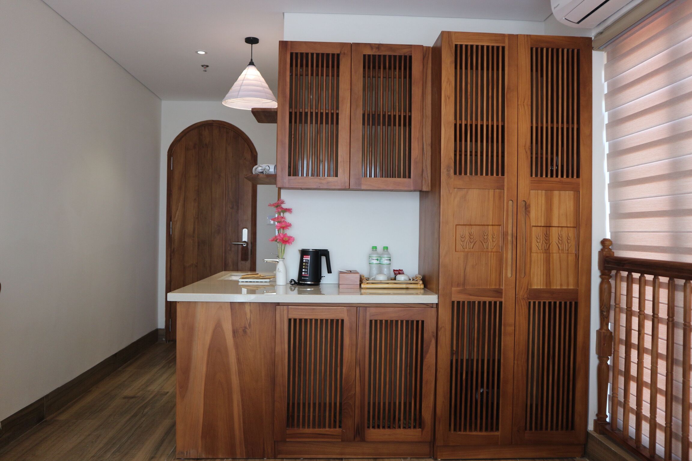 A wooden cabinet with a built-in sink, a hanging light fixture, and a wooden door with a window.