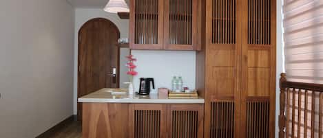 Un mueble de madera con lavamanos integrado, una lámpara colgante y una puerta de madera con ventana.