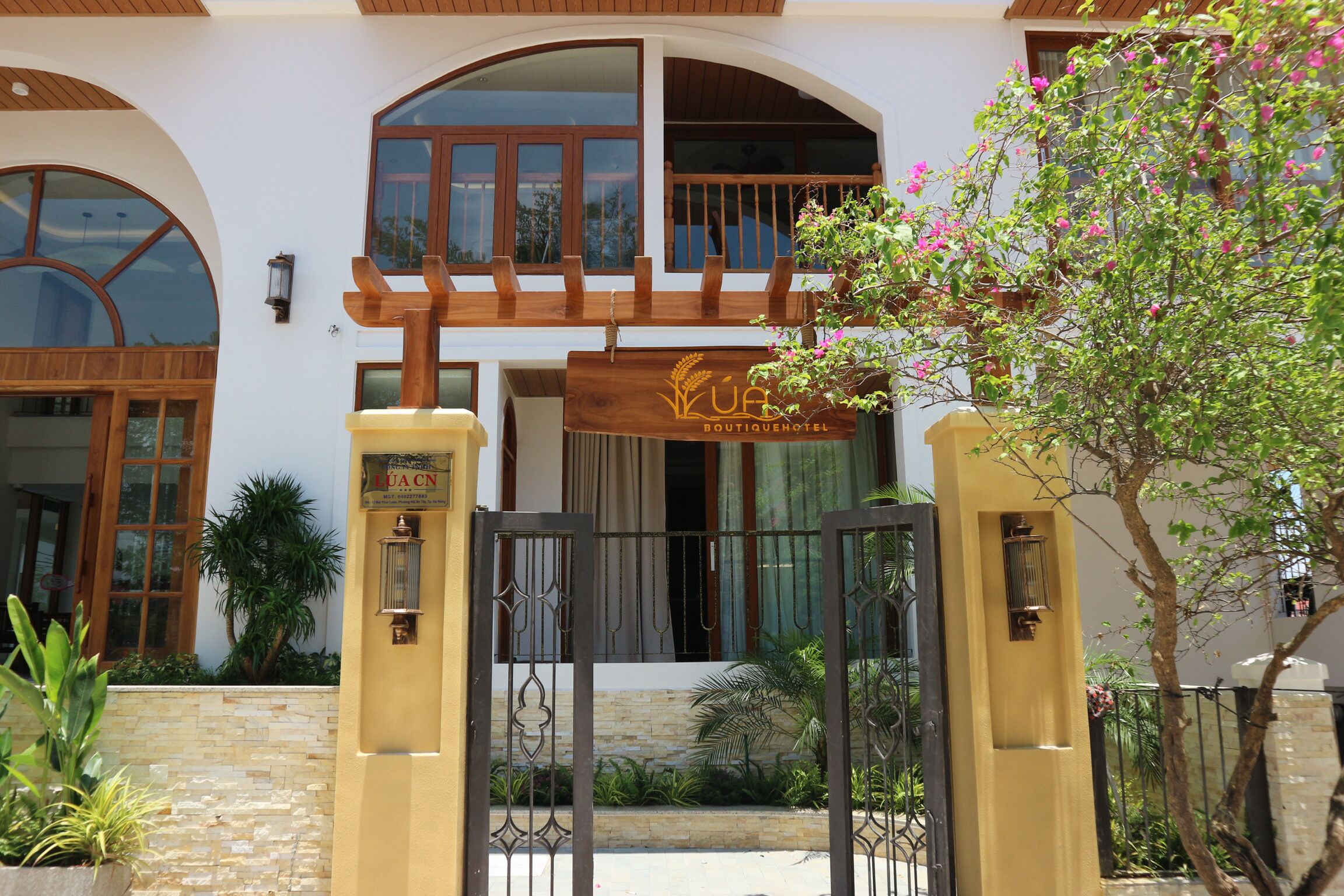 A hotel entrance with a wooden gate, a signboard, and a balcony.
