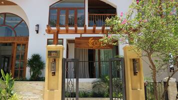A hotel entrance with a wooden gate, a signboard, and a balcony.