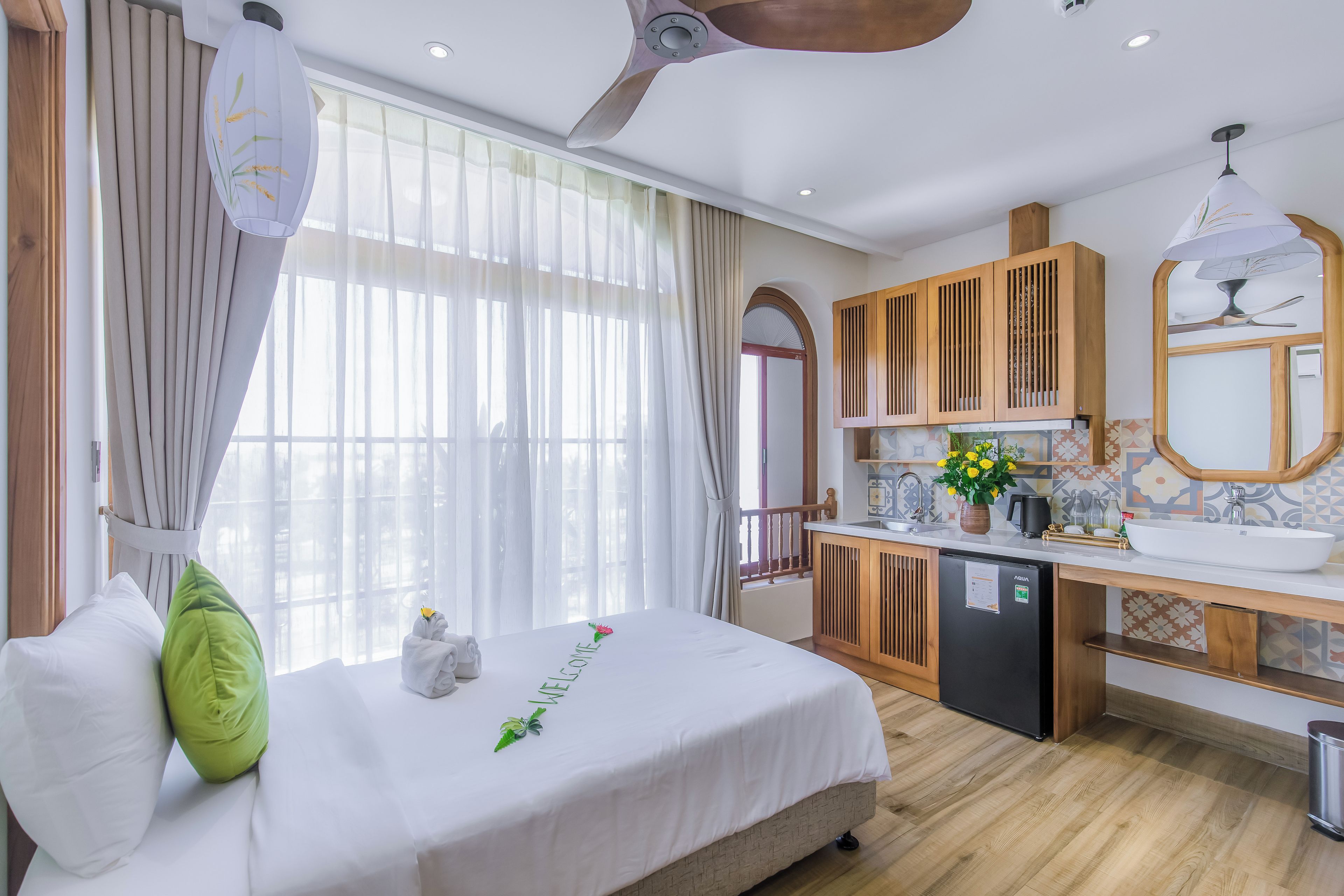 A hotel room with a bed, a small kitchenette, and a bathroom.