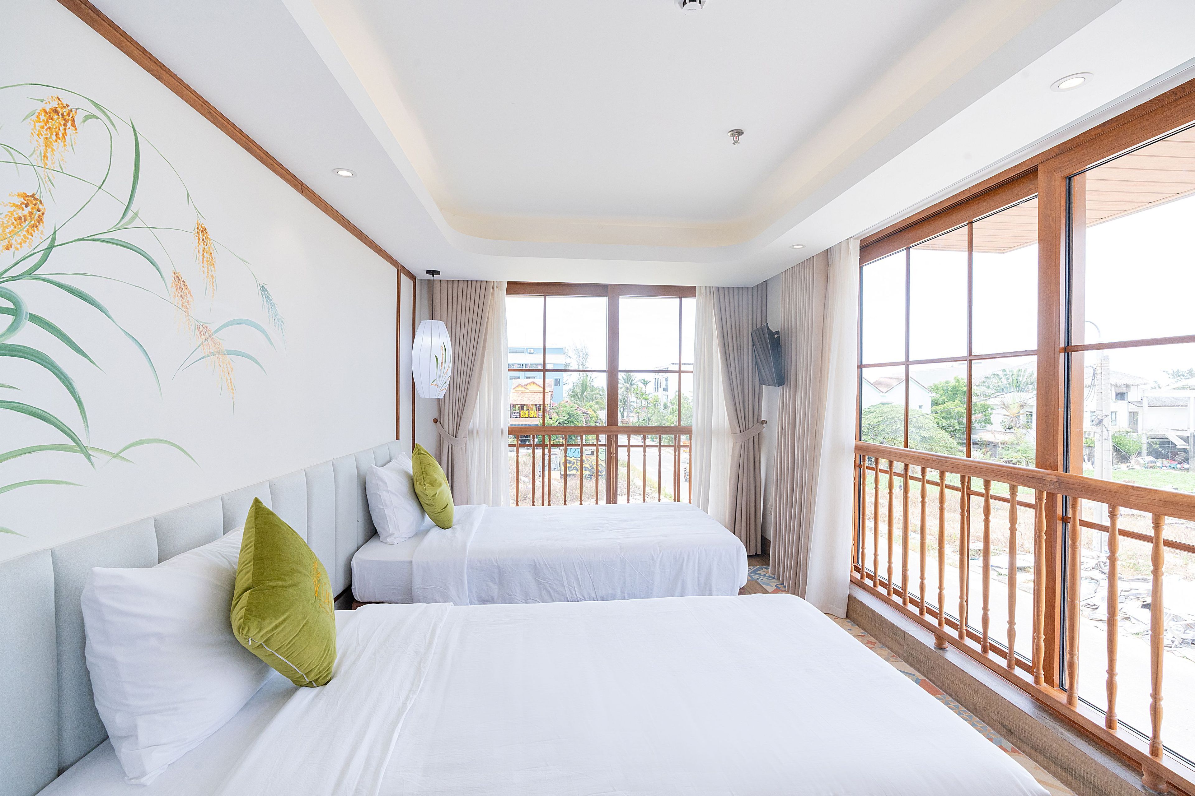 A hotel room with two beds, a large window with a view, and a wall with a floral mural.