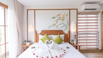 Una habitación de hotel con una cama grande, un cabecero con diseño floral, un aire acondicionado de pared y una ventana con persianas.