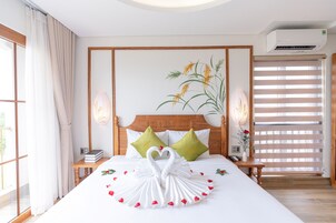 Una habitación de hotel con una cama grande, un cabecero con diseño floral, un aire acondicionado de pared y una ventana con persianas.