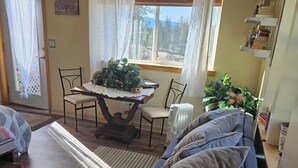 Una sala de estar con un sofá, una mesa con plantas, un radiador y una ventana con persianas.