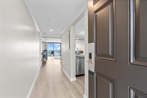 Ein Flur mit Küchenzeile, einem Edelstahlkühlschrank und Blick auf einen Balkon.