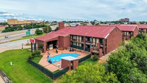 Un edificio con techo rojo, piscina y vistas a una autopista y al paisaje urbano.