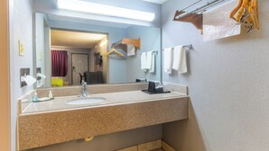 Un baño con encimera de granito, lavabo, espejo, toallero y perchero.
