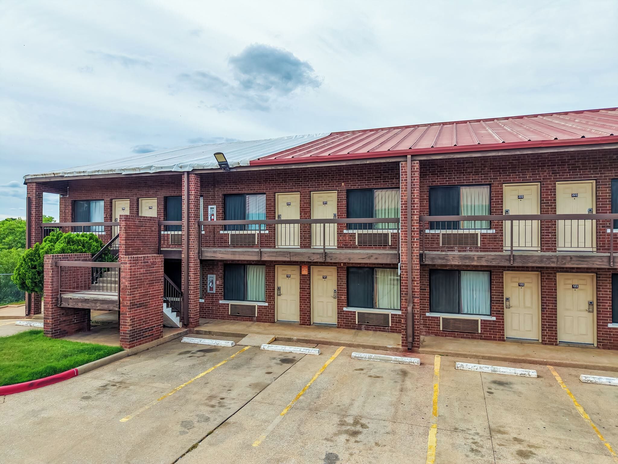 A multi-story motel with a brick facade, multiple balconies, and a parking lot.