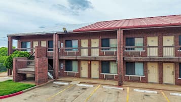 A multi-story motel with a brick facade, multiple balconies, and a parking lot.