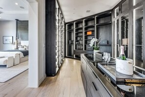 Ett modernt hotellrum med en stor klädkammare, en matplats med en bänkskiva i marmor och en säng med ett vitt sänggavel.