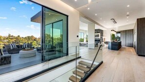 A modern interior with a staircase, a dining area, and a view of the outdoors. - Casa Adriana by Oraklus (Pacific Palisades)