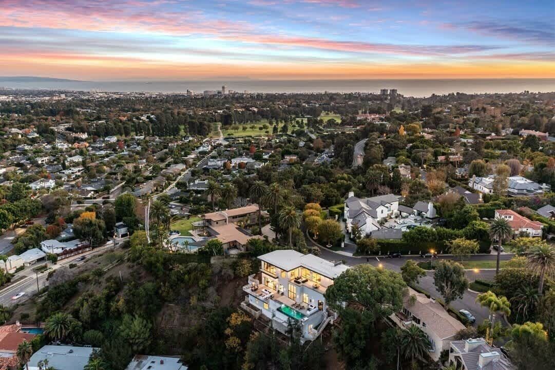 An aerial view of a residential area with houses, roads, and a large body of water in the distance.