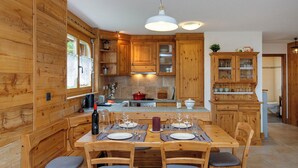 Un intérieur en bois comprenant une table à manger pour quatre personnes, des armoires en bois et un coin cuisine.