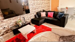 A living room with a brick wall, a black sofa, a white coffee table, and a red rug. - Stylish 2BR Apartment Parking PS5 Wifi (Darwen)
