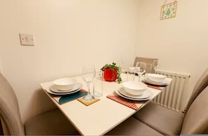 A dining table set with plates, glasses, and a small potted plant.