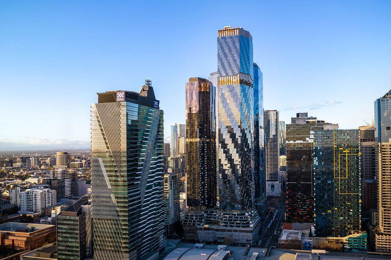 A cityscape with modern skyscrapers, including a distinctive building with a reflective facade and another with a unique geometric design.