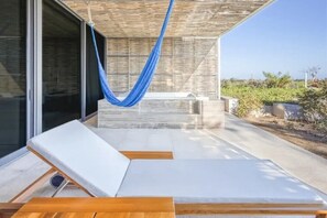 A modern outdoor lounge area with a hammock, white lounge chairs, and a view of the landscape. - The Club at Solaz - Two Bedroom Villa Ocean View New Years Eve Week (San José del Cabo)