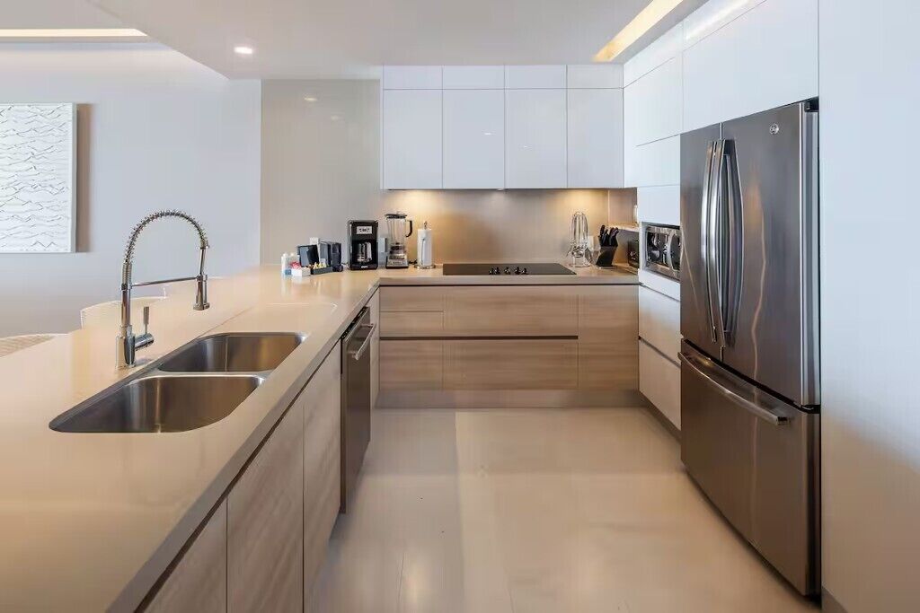 A modern kitchen with stainless steel appliances, a double sink, and light wood cabinetry.