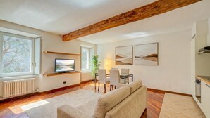 Una sala de estar con sofá, televisor, mesa de comedor, sillas y obras de arte en la pared.