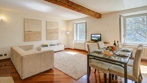 Una sala moderna con una mesa de comedor de cristal, sofás beige y una viga de techo de madera.