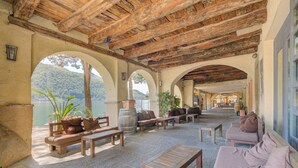 Un patio al aire libre con suelo de piedra, mobiliario de madera y vistas a un lago.