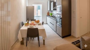 Une cuisine moderne avec un coin repas, des poutres apparentes en bois au plafond et une grande fenêtre.