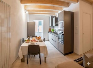 Eine moderne Küche mit Essbereich, Holzbalkendecke und einem großen Fenster.