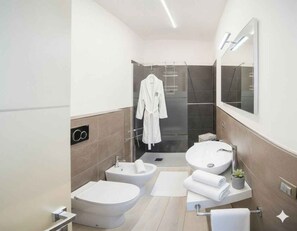 A modern bathroom with a bidet, two sinks, a glass shower enclosure, and a robe hanging on a rack. - Holiday apartment mit Klimaanlage und Balkon (Imperia)