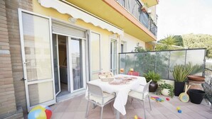 Un patio con tavolo apparecchiato per mangiare, circondato da vasi di piante e giocattoli per bambini.