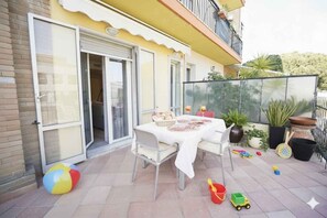 A patio with a table set for dining, surrounded by potted plants and children's toys. - Holiday apartment mit Klimaanlage und Balkon (Imperia)
