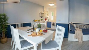 Un coin repas avec une table dressée pour deux personnes, un lave-linge et un canapé en arrière-plan.