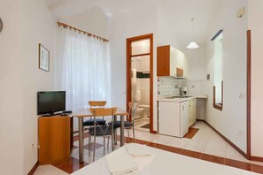 A compact kitchen with a dining area, a television, and a small cabinet. - Studio with air conditioning (Medulin)