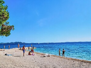 Ein Strand mit Menschen, einem klaren Himmel und dem Meer.