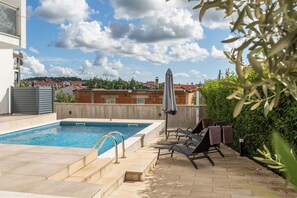 A rooftop pool area with lounge chairs and a view of the cityscape. - Villa Keke (Rovinj)