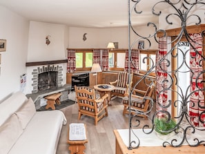 Una sala de estar acogedora con chimenea, muebles de madera y vistas al exterior.