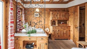 A wooden cabin interior with a dining area, a radio on a shelf, and a small table. - Chesa Minchületta by Interhome (Silvaplana-Surlej)