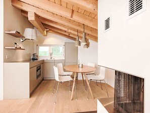 A modern kitchen with wooden beams, white cabinets, and a dining area with a round table and chairs. - Cocoon-Laax by Interhome (Laax)
