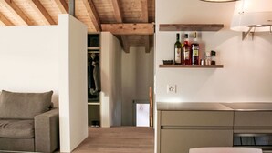 Un interior moderno con un sofá, una mesa de comedor, una cocina con horno empotrado y techo de madera.
