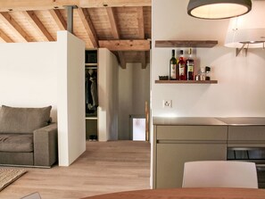 A modern interior with a sofa, a dining table, a kitchen with a built-in oven, and a wooden ceiling. - Cocoon-Laax by Interhome (Laax)