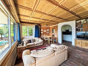 A cozy living room with a wooden ceiling, a dining area, and a kitchen with wooden cabinets. - Casa Sur Vitg by Interhome (Laax)