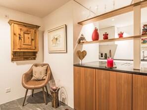 Uma cozinha moderna com armários de madeira, bancada preta, uma cadeira, um quadro e uma decoração em formato de coração.