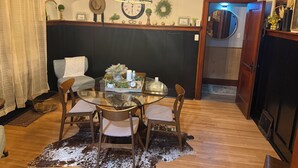 Un coin repas avec une table en verre, des chaises, une horloge et une guirlande décorative accrochée au mur.