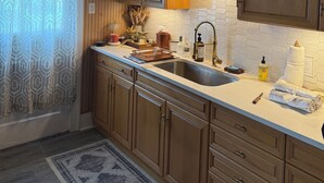 Une cuisine moderne avec des meubles en bois, un plan de travail blanc, un évier et un luminaire décoratif au plafond.