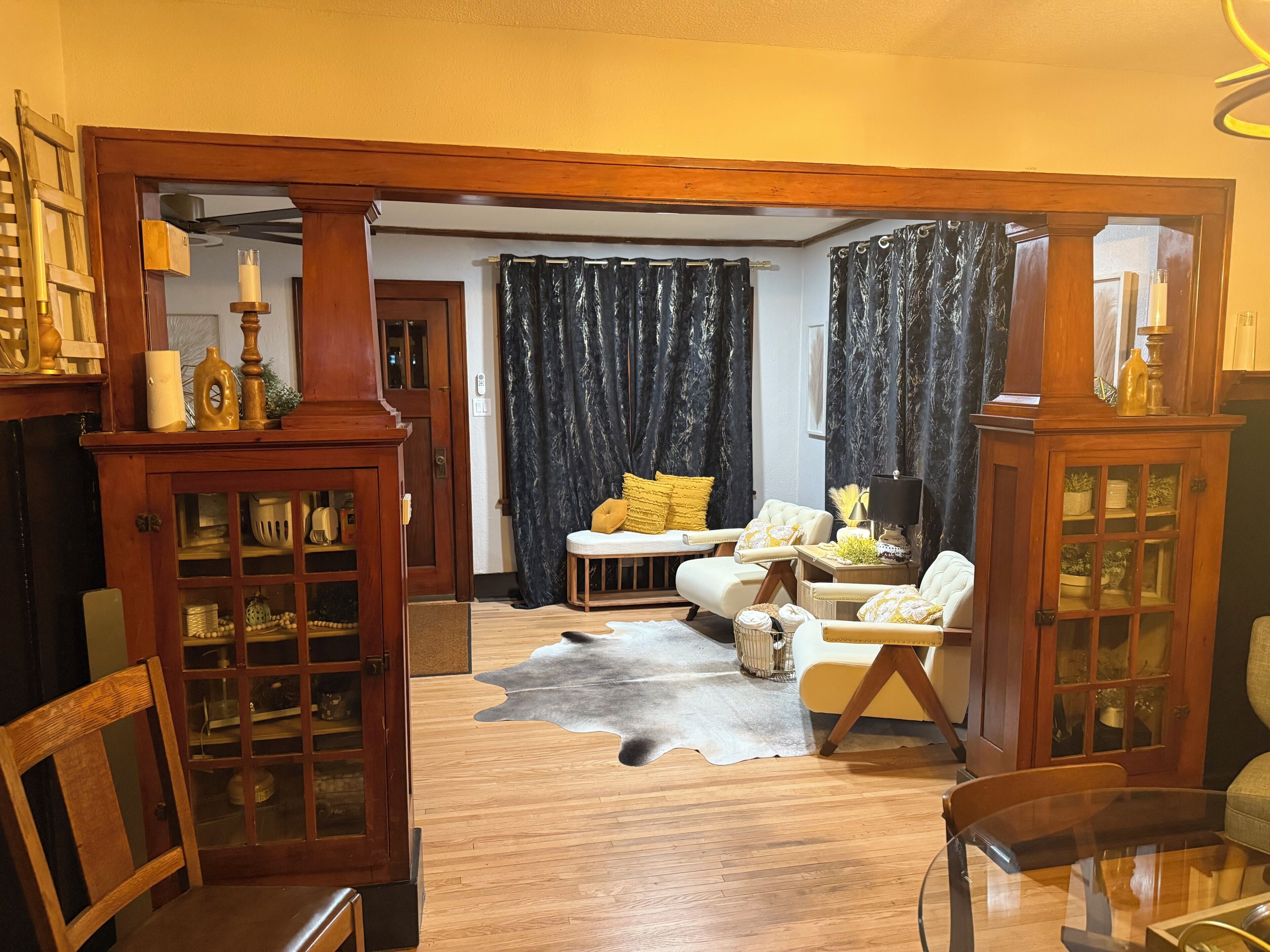 Un salon avec un plancher en bois, une table basse en verre, un canapé et un fauteuil.