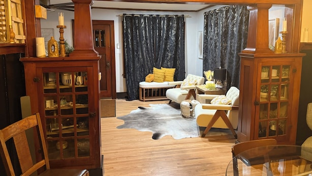 Un salon avec un plancher en bois, une table basse en verre, un canapé et un fauteuil.