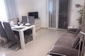 A modern living space with a dining area, a sofa, a TV, and a sliding glass door. - Batur Pool Apartment A4, Zadar, Croatia (Zadar)
