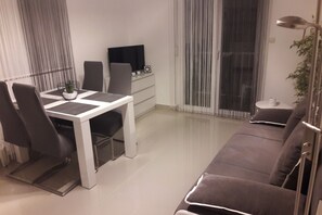 A modern living room with a sofa, a dining table with chairs, a TV, and a plant. - Batur Pool Apartment A4, Zadar, Croatia (Zadar)