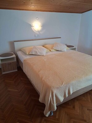 Une chambre à coucher avec un lit, des tables de chevet, une lampe fixée au mur et un plafond en bois.