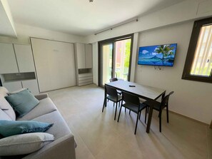 Eine moderne Küche mit Essbereich, einer Couch und einem Fernseher an der Wand.